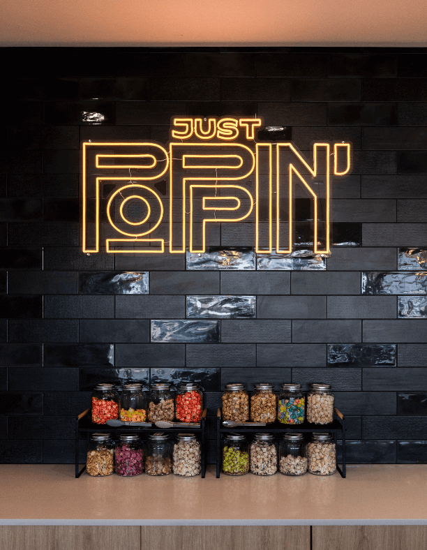 Custom LED signage, circular feature pendant lights and black and orange colour palette for this retail fit out for Just Poppin'
